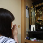 仏壇に手を合わせる女性